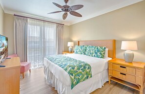 A hotel room with a bed, two bedside tables, a ceiling fan, a TV, and a window with curtains.