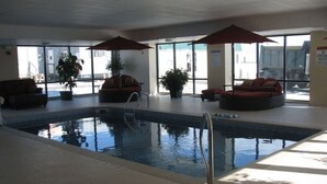 An indoor swimming pool with lounge chairs and umbrellas, surrounded by large windows. - *Modern*GRAND VICTORIAN*OCEAN VIEW*FAMOUS PIER *3 BEDRM*UNIT 510 (Old Orchard Beach)