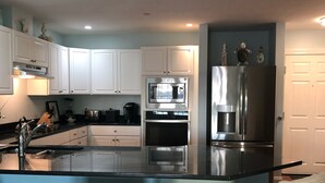 A modern kitchen with white cabinets, stainless steel appliances, and a central island with bar stools.