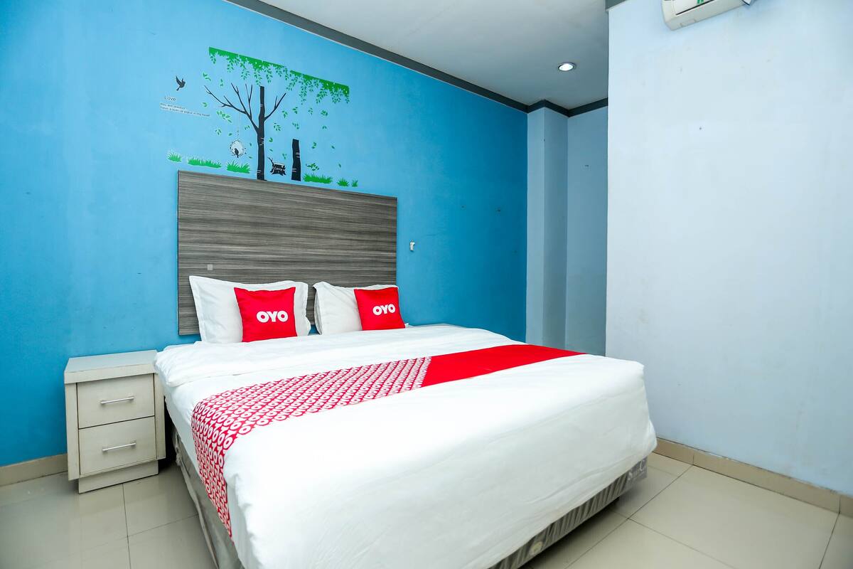 Une chambre à coucher avec un lit, une table de chevet et une fresque murale.