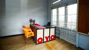 Habitación con mostrador de recepción, piso de madera y ventana con cortinas estampadas.