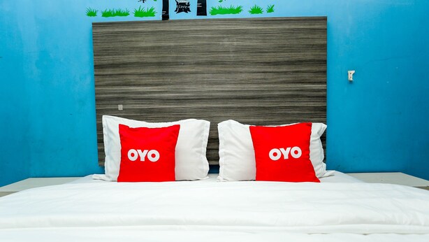 Una cama con ropa de cama blanca y dos almohadas con diseños rojo y blanco.