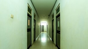 Un pasillo largo y estrecho con puertas a ambos lados, que conduce a una habitación luminosa al final.