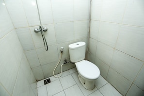 Un baño pequeño y limpio, con azulejos blancos, un inodoro y una ducha.