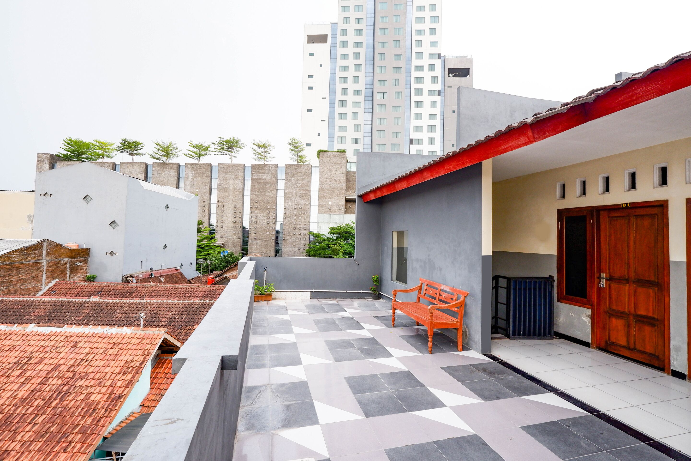 A rooftop terrace with a checkered floor, a wooden bench, and a red awning.