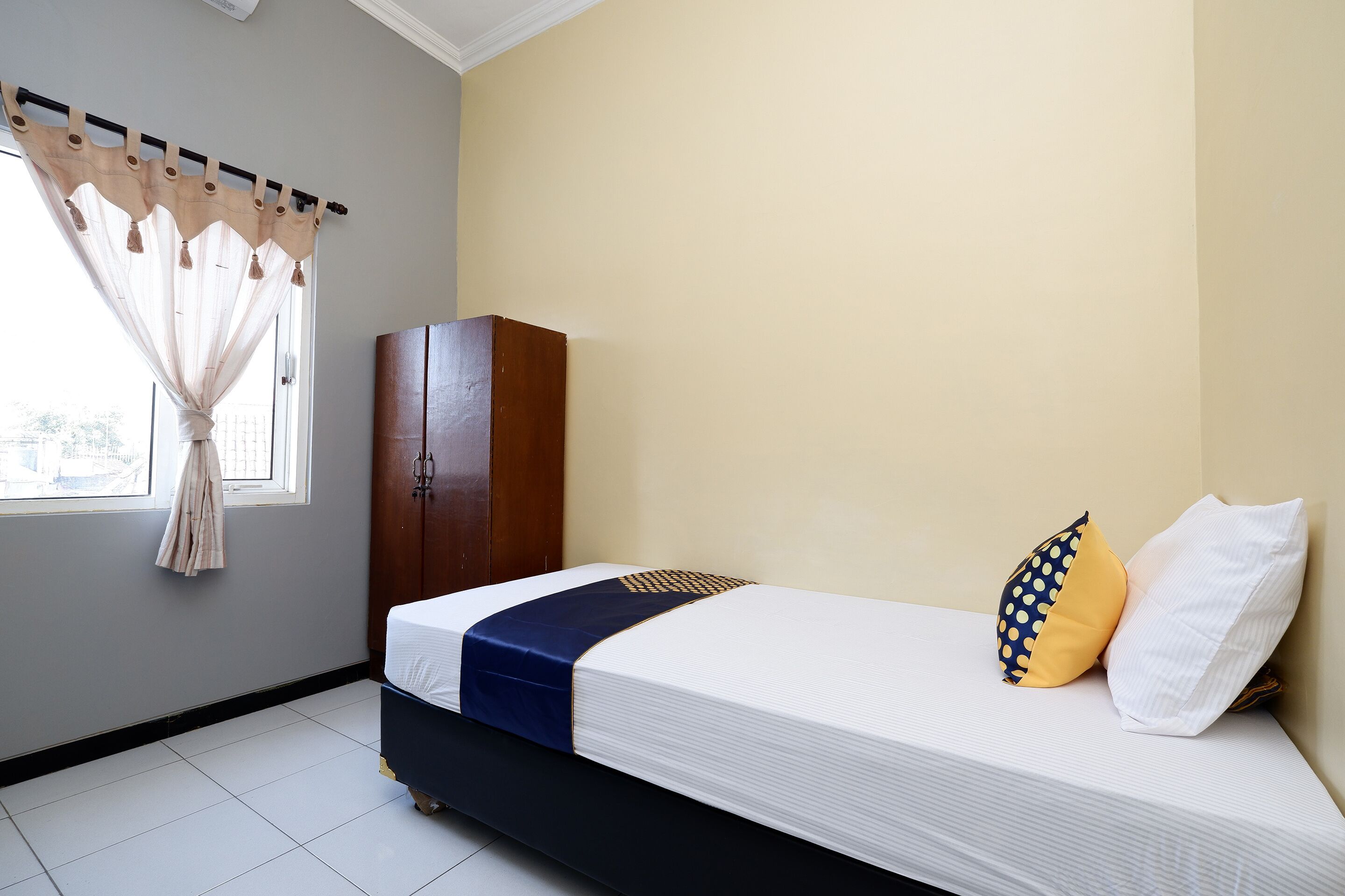 A bedroom with a bed, a wardrobe, and a window with curtains.