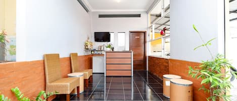 Un vestíbulo de hotel con mostrador de recepción, zona de estar y una televisión.