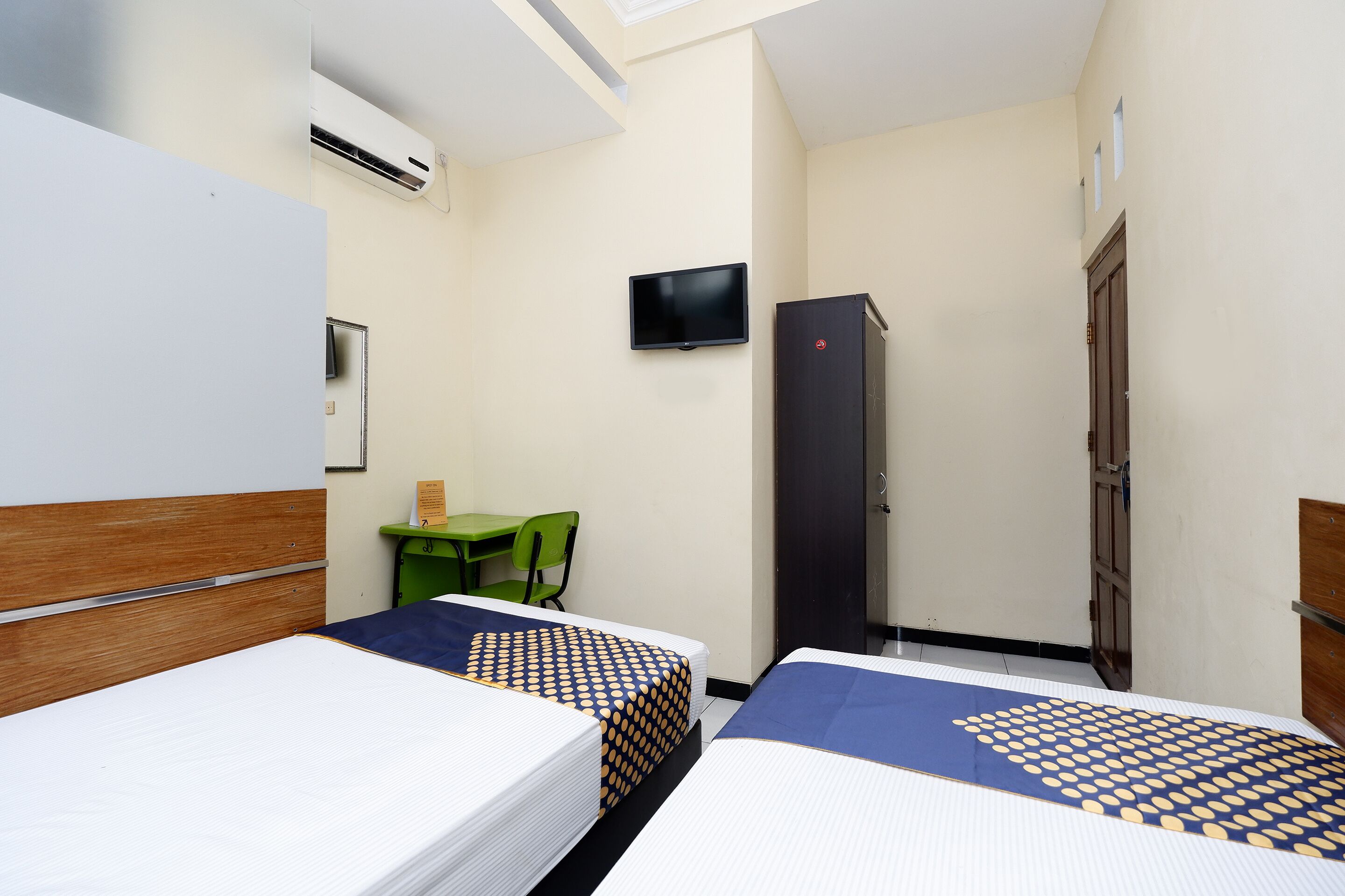 A hotel room with two beds, a desk, a TV, and a wardrobe.