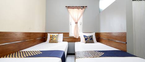 Una habitación de hotel con dos camas individuales, una ventana con cortinas y vistas a la calle.
