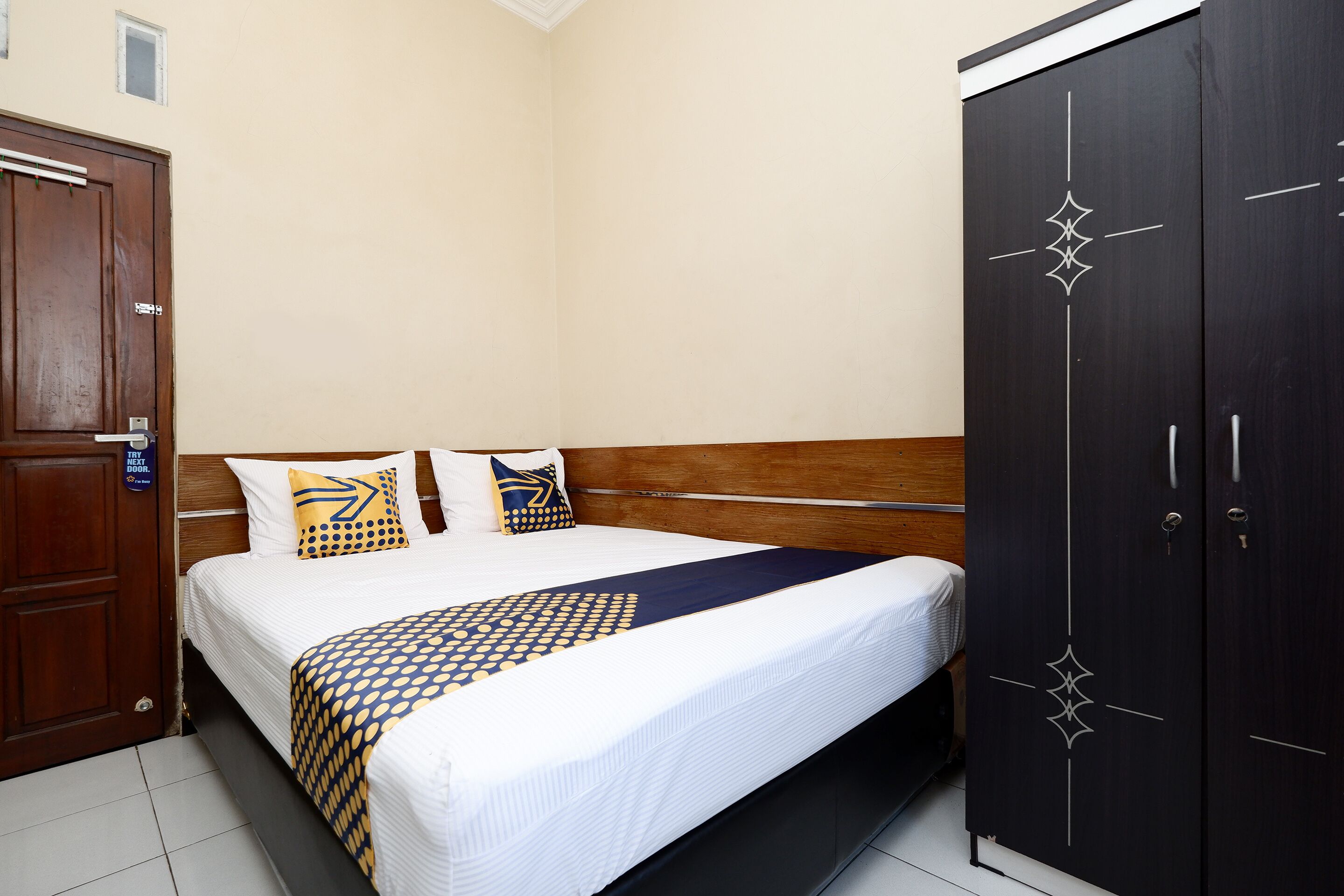 A neatly made bed with a patterned bedspread, a wooden headboard, and two pillows.