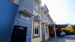 Un immeuble à plusieurs étages, doté d’une façade jaune et grise, d’une entrée couverte et d’une antenne parabolique sur le toit.
