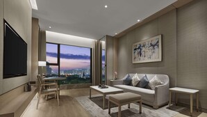 A modern living room with a large window, a sofa, a coffee table, and a TV. - DoubleTree by Hilton Shenzhen Nanshan Hotel & Residences (Shenzhen)