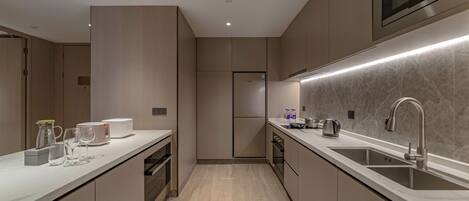 A modern kitchen with a built-in microwave, stainless steel sink, and a sleek countertop.
