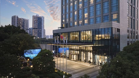 A modern hotel with a glass facade, multiple floors, and a flag on the roof.