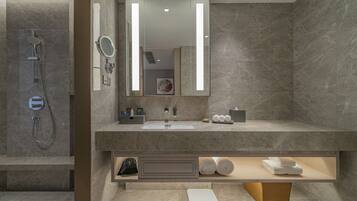 A modern bathroom with a large mirror, a shower, and a vanity with a sink and towel rack.