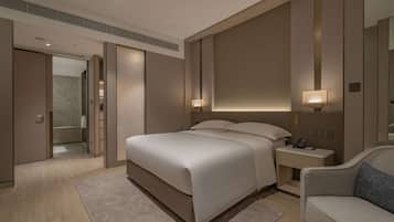 A modern hotel room with a large bed, bedside tables, a nightstand, a sofa, and a walk-in closet.