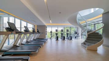 A modern gym with treadmills, stationary bikes, and a spiral staircase.