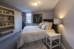 Relax in this serene bedroom with a large bed, shelving unit, and a window offering a view of the outside.