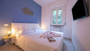 A bedroom with a bed, bedside table, lamp, and a wall-mounted TV. - Cervo Piccolo Incanto Apartment with Balcony, Cervo, Italy (Cervo)