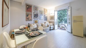 A modern kitchen with a dining area, featuring a white table set with plates, glasses, and cutlery. There is a sofa and a refrigerator in the background. - Cervo Piccolo Incanto Apartment with Balcony, Cervo, Italy (Cervo)