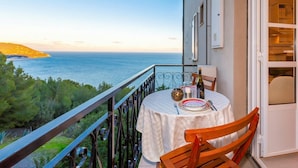 A balcony with a table set for two, overlooking a body of water and greenery. - Cervo Piccolo Incanto Apartment with Balcony, Cervo, Italy (Cervo)