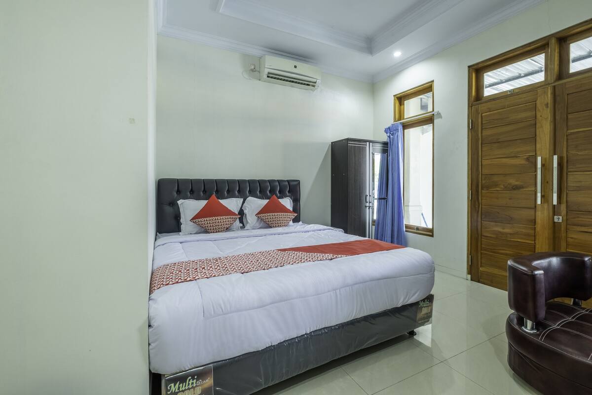A bedroom with a bed, a wardrobe, and a seating area.