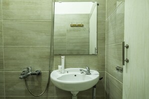 A bathroom with a white sink, a mirror, and a shower.
