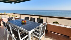 Ein Balkon mit Tisch und Stühlen mit Blick auf einen Strand und das Meer.