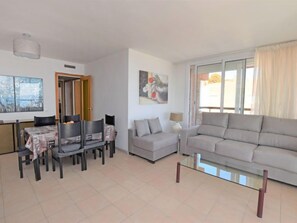 Una sala moderna con un sofá gris, una mesa de comedor con sillas y un cuadro en la pared.