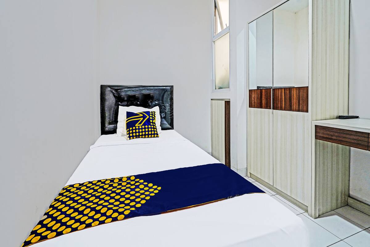 A small, modern bedroom with a bed, a nightstand, a mirror, and a wardrobe.
