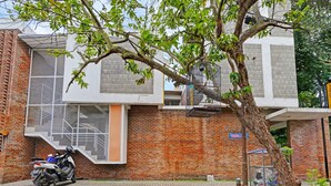 Un edificio moderno con facciata in mattoni, una scala in metallo e un albero di fronte.