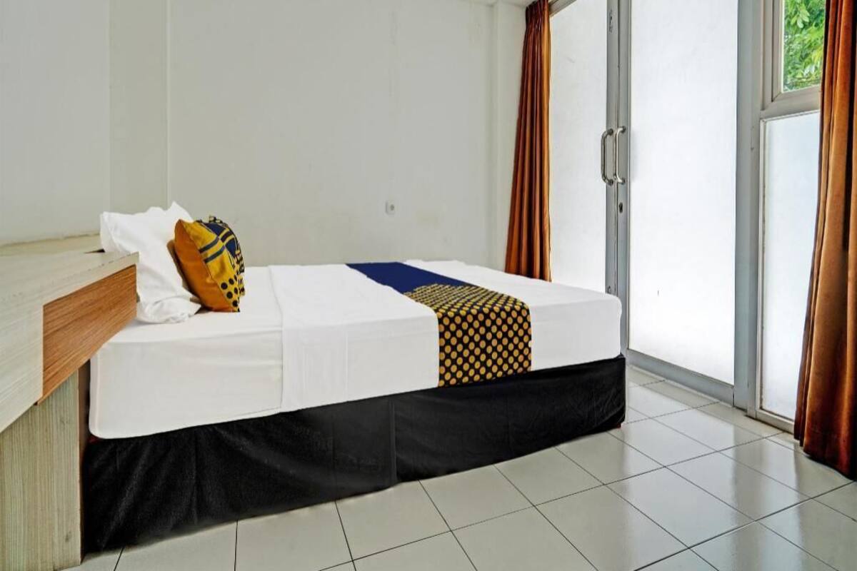 A single bed with a white mattress, a black skirt, and a patterned blanket.
