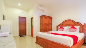A bedroom with a wooden bed, white bedding, and red pillows. - OYO 2143 Leluhur Bali Apartment (Keroboken Kelod)