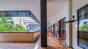 A spacious indoor area with a tiled floor, a central column, and a seating area with chairs. - OYO 2143 Leluhur Bali Apartment (Keroboken Kelod)