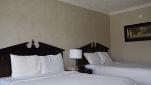 A hotel room with two beds, a nightstand with a lamp, and a framed picture on the wall. - Festival Courtyard Inn (Stratford)