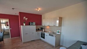 A compact kitchen with white cabinets, a built-in oven, and a sink. - Apartment 3 - Jack & Richies apartments (Greifswald)