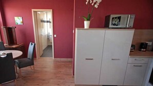 A compact kitchen with white cabinets, a microwave, and a coffee maker. - Apartment 3 - Jack & Richies apartments (Greifswald)