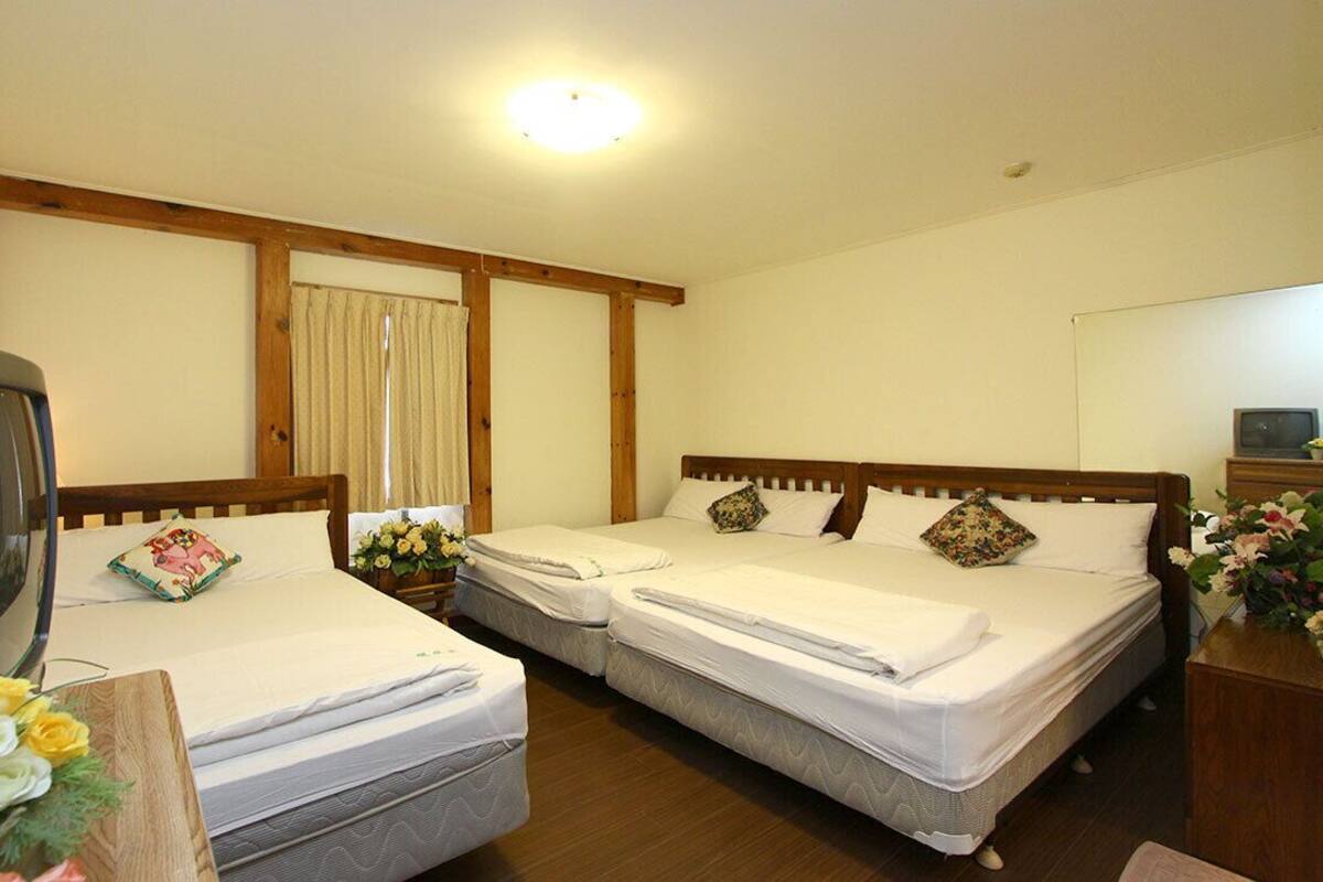 A hotel room with two single beds, a television, and a wooden headboard.