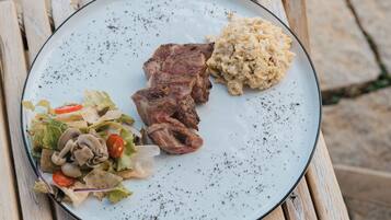 A plate with grilled meat, mashed potatoes, and a salad on a wooden table.