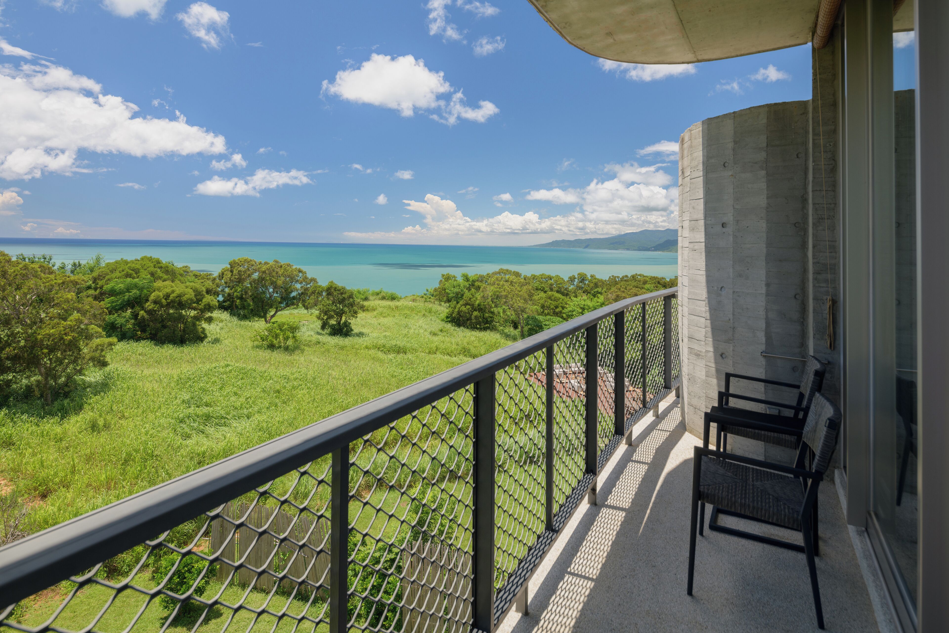 A balcony with a view of a green landscape and a body of water.