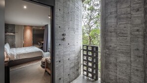A modern bedroom with a large bed, a wooden headboard, and a view of greenery outside. - Wandering Walls (Hengchun)