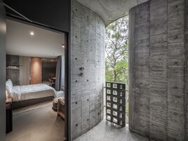 Un dormitorio moderno con una cama grande, cabecera de madera y vistas a zonas verdes.