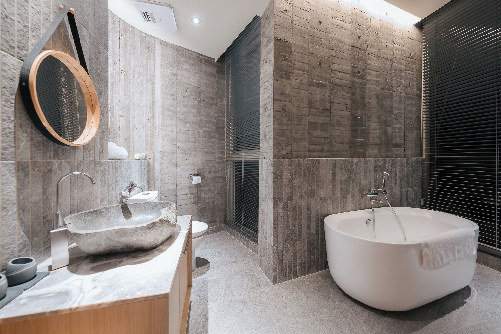 Een moderne badkamer met een groot bad, een vrijstaand wastafelmeubel en een ronde spiegel.