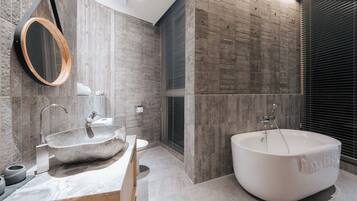 Een moderne badkamer met een groot bad, een vrijstaand wastafelmeubel en een ronde spiegel.