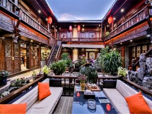 A traditional courtyard with wooden architecture, a central seating area, and potted plants. - Floral Hotel · He Lu Ju Lijiang (Lijiang)