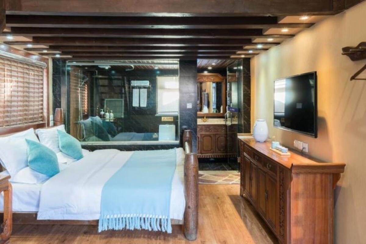 Un dormitorio con cama, televisor y techo de madera.