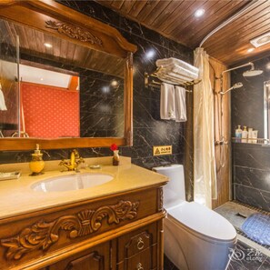 A bathroom with a marble sink, wooden vanity, and a shower area.