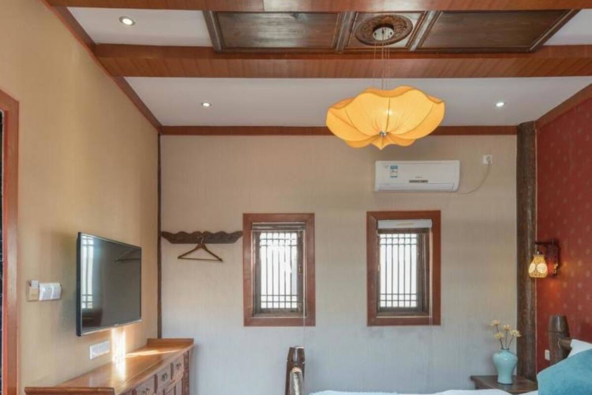 Un dormitorio con cama, muebles de madera, televisor y aire acondicionado.