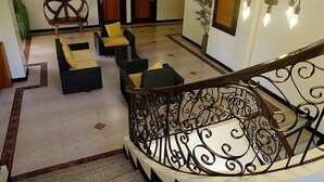 A hotel lobby with a staircase, seating area, and a large decorative chair. - Momarco Forest Cove Resort And Hotel (Tanay)