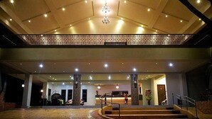 A hotel lobby with a high ceiling, a chandelier, a reception desk, and a staircase leading to an upper level. - Momarco Forest Cove Resort And Hotel (Tanay)